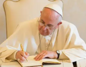 Papa Francisco escribiendo a mano sobre una agenda.