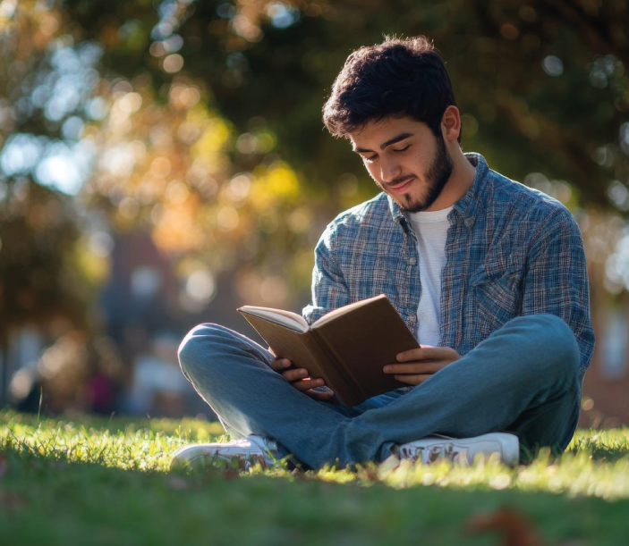 Joven al aire libre sentado mientras lee la Biblia.